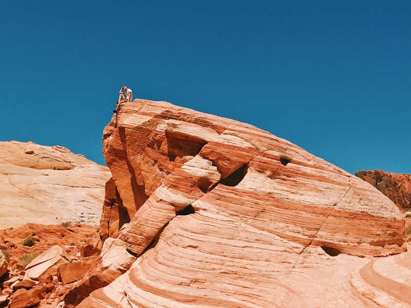 A person sitting on a rock formation on the Fire Wave trail in the Valley of Fire