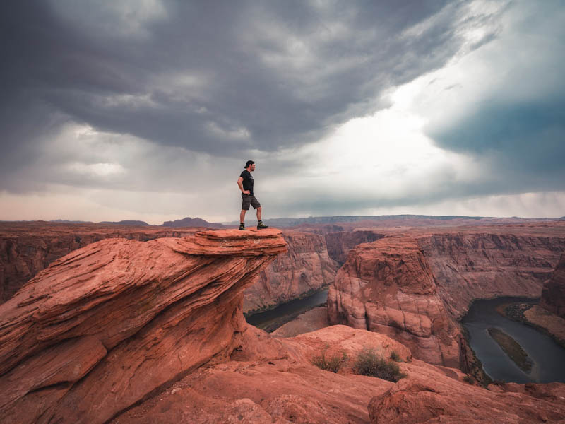 A man standing on a rock outcropping, high up at the Grand Canyon