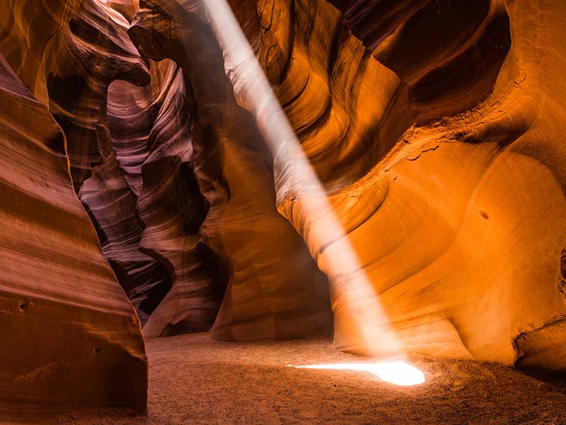 A light beam shining down into Antelope Canyon and illuminating the rock walls