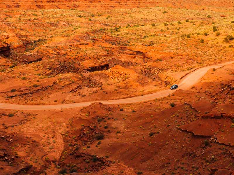 An aerial view of a car driving through Monument Valley