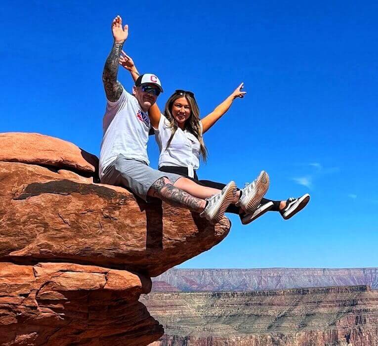 Couple sitting and posing at the edge of the Grand Canyon